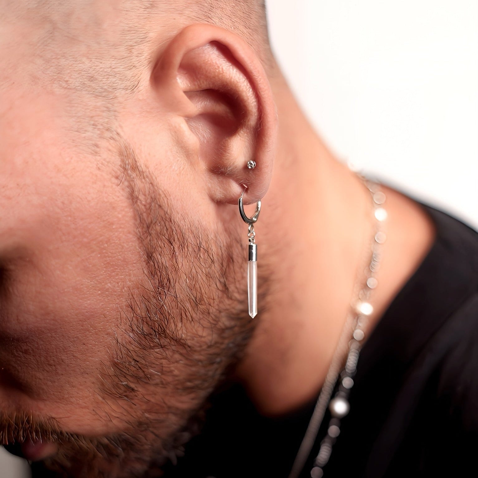 Close-up of a person wearing a dangling MHART Quartz Spike earring with a neutral background