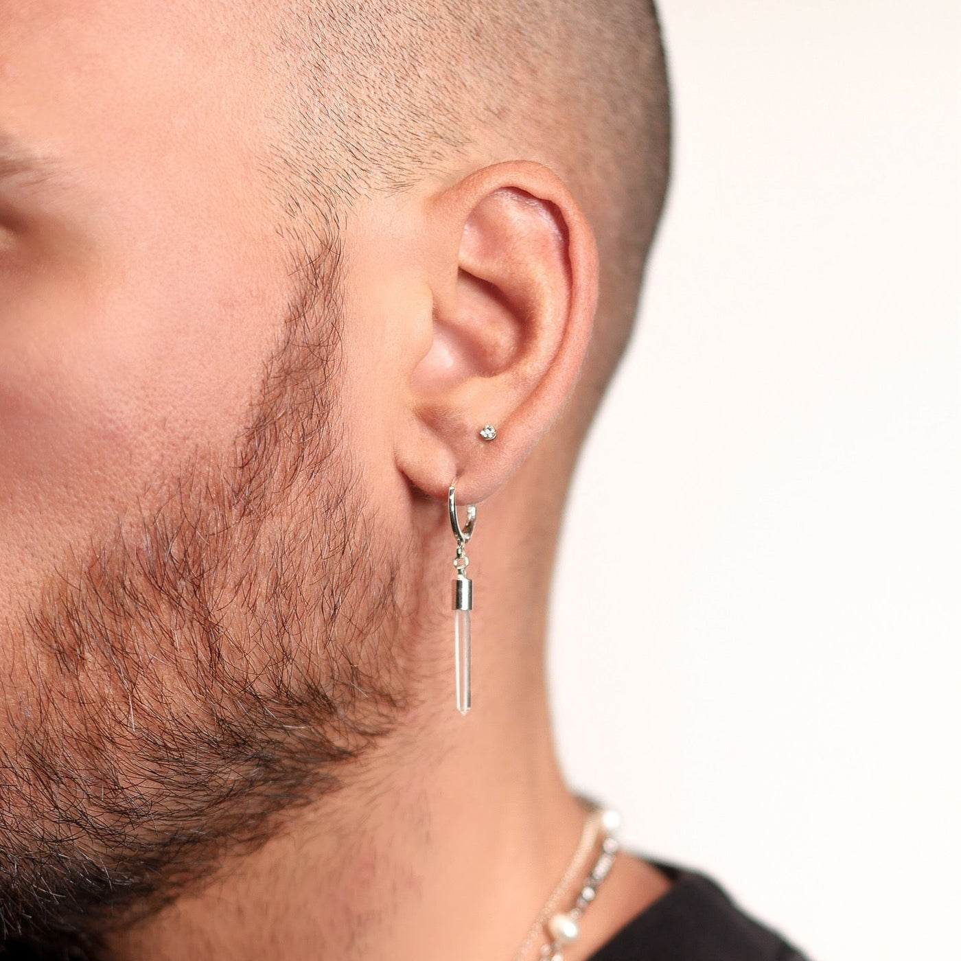Close-up of a man wearing a MHART silver earring with a quartz gemstone spike